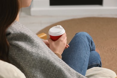 Photo of Woman holding takeaway cardboard cup indoors, closeup. Coffee to go