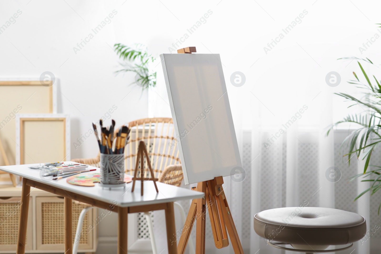 Photo of Table with paints and tools near easel in art studio
