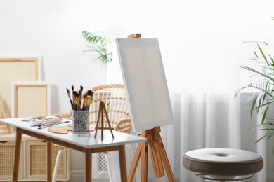 Photo of Table with paints and tools near easel in art studio