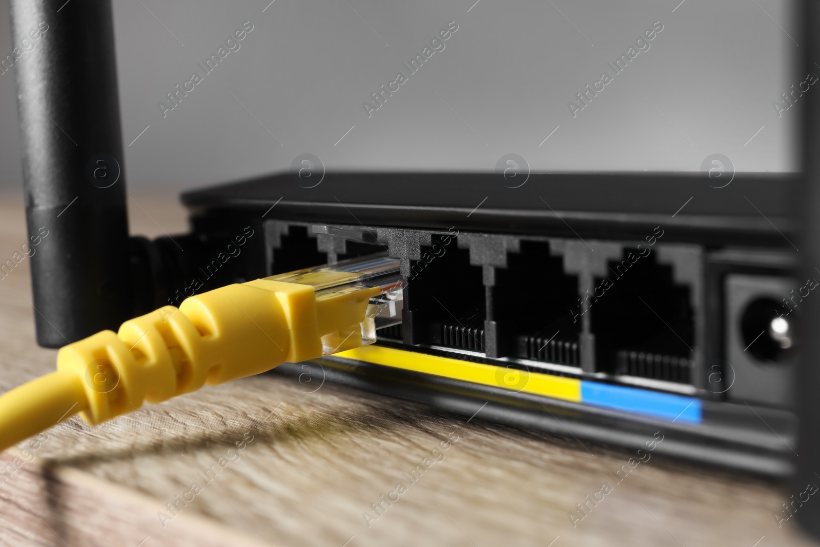 Photo of Connected cable to router on wooden table, closeup. Wireless internet communication