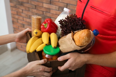Photo of Male courier delivering food to client indoors, closeup