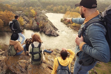 Group of friends with backpacks enjoying beautiful view near mountain river
