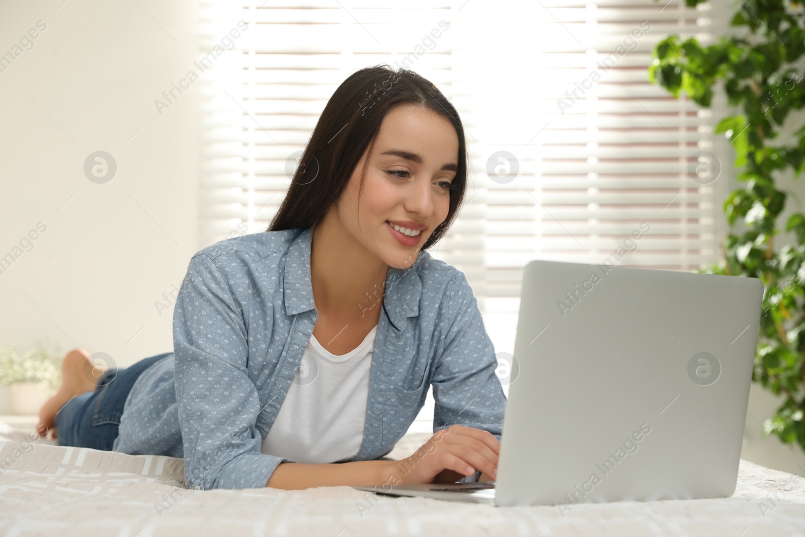 Photo of Woman using laptop for search on bed at home