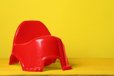 Photo of Red baby potty on yellow background, space for text Toilet training