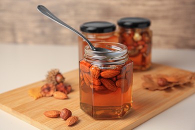 Jars with different nuts and honey on beige table