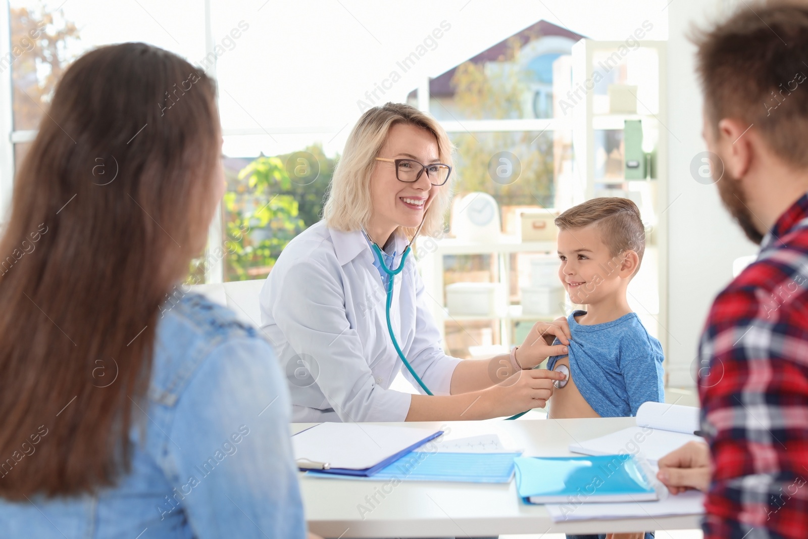 Photo of Children's doctor examining little boy with stethoscope in hospital