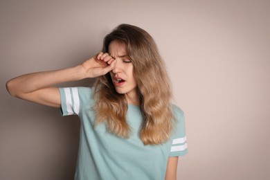 Photo of Young tired woman yawning on beige background