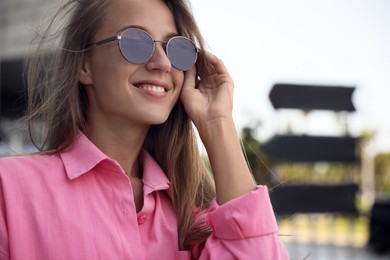 Photo of Beautiful young woman in stylish sunglasses outdoors, closeup