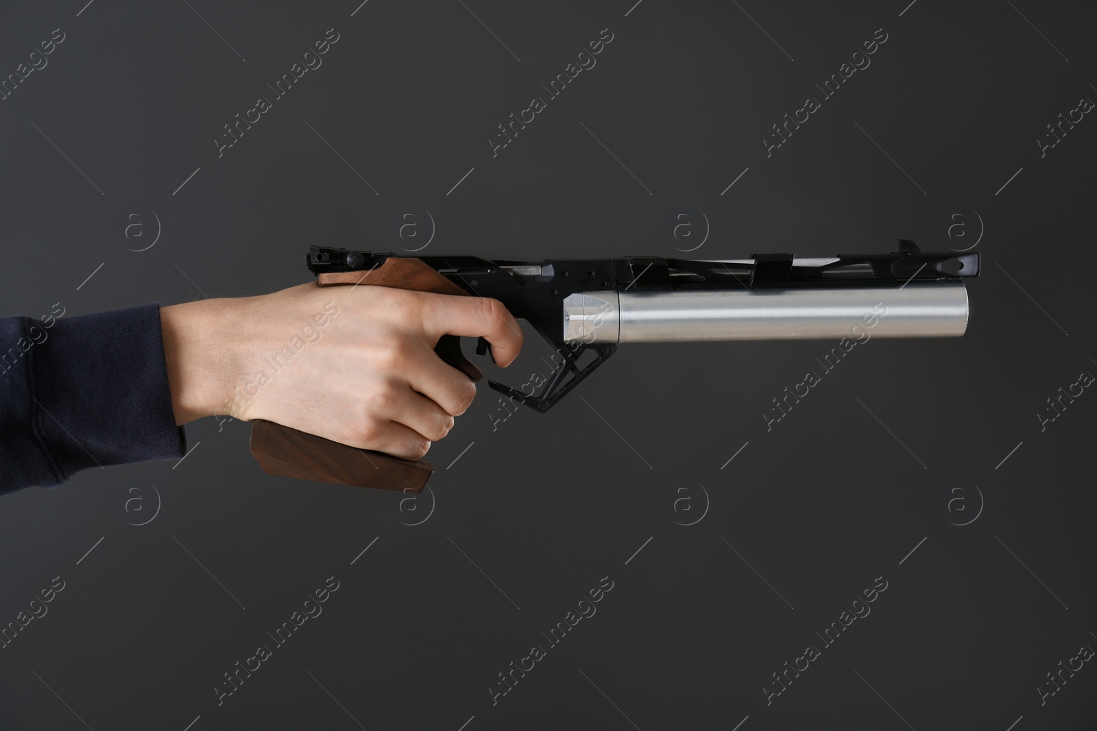 Photo of Gun shooting sport. Man aiming standard pistol on dark background, closeup