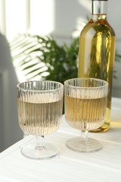 Alcohol drink in glasses and bottle on white wooden table indoors