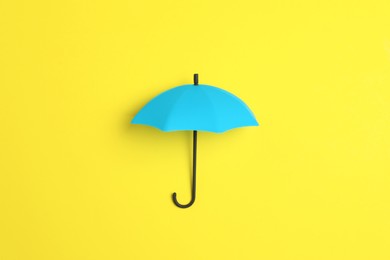 Photo of Bright toy umbrella on yellow background, top view