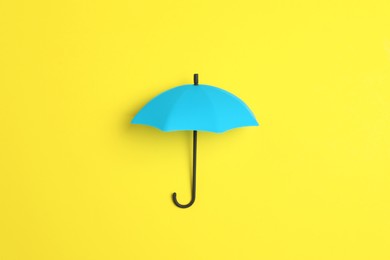 Bright toy umbrella on yellow background, top view