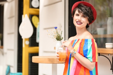 Photo of Young woman with cup of tasty lemonade outdoors