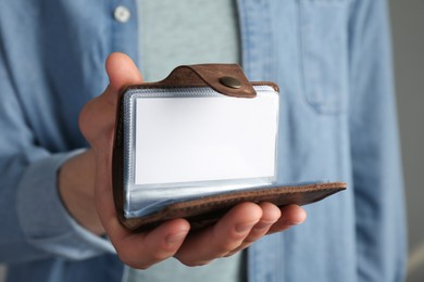 Photo of Man holding leather business card holder with blank card, closeup