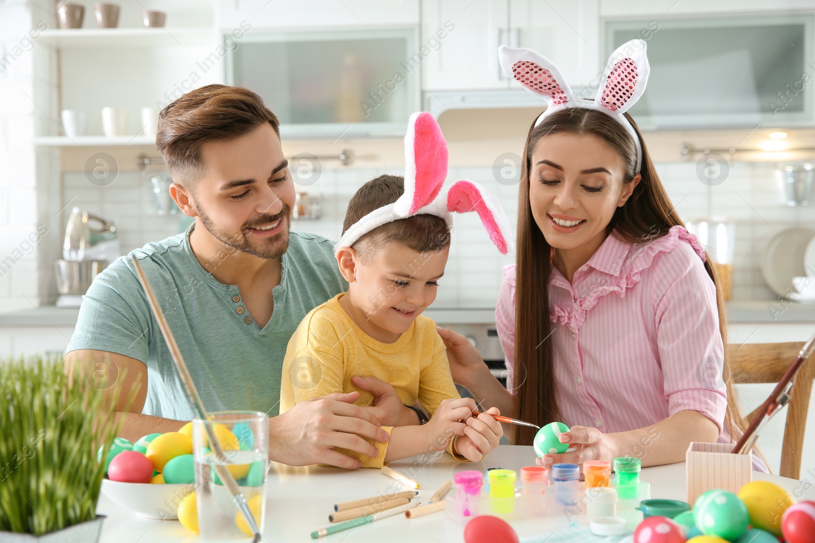 Photo of Happy family painting Easter eggs in kitchen. Festive tradition