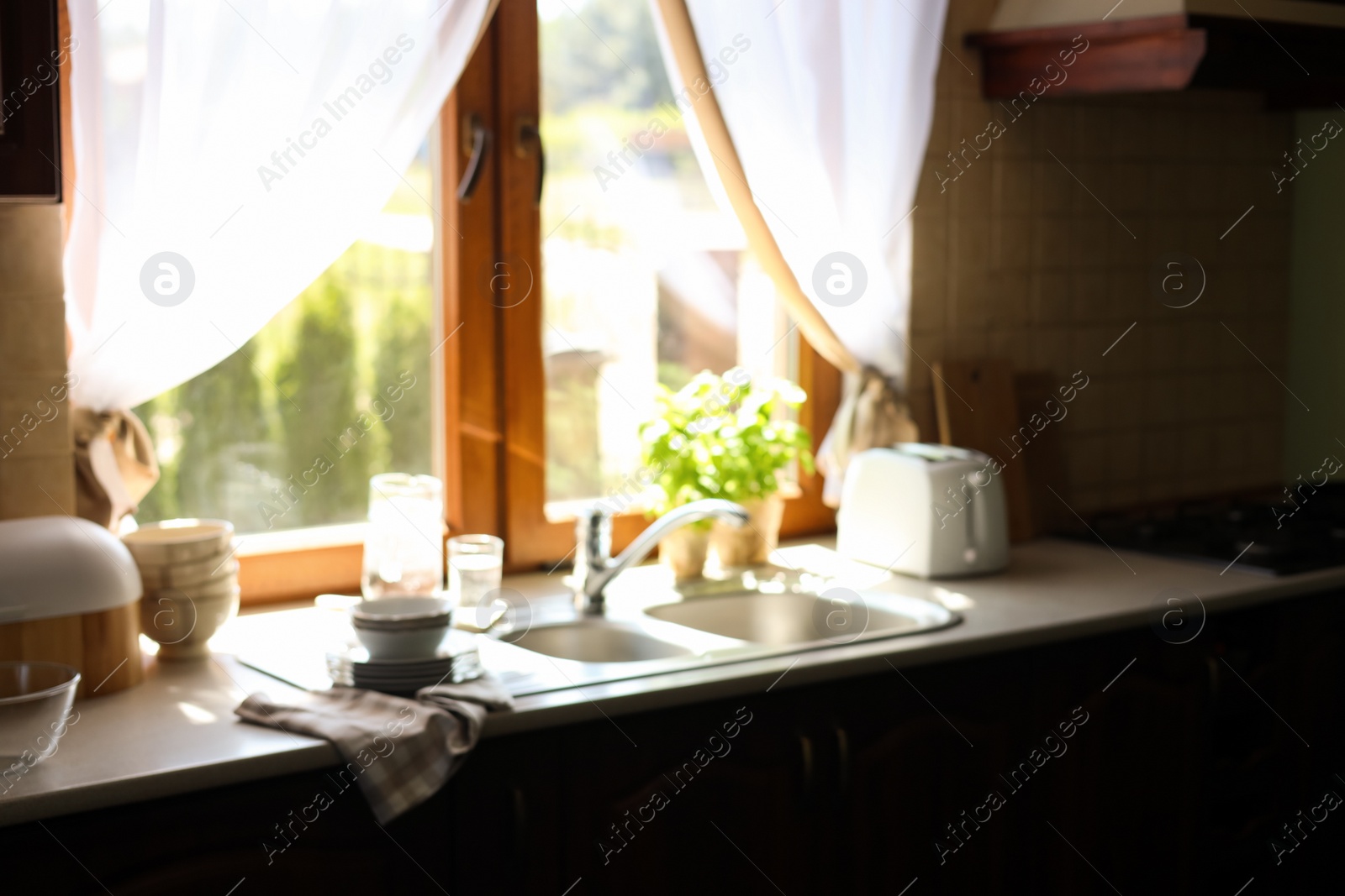 Photo of Blurred view of stylish kitchen interior with sink near window