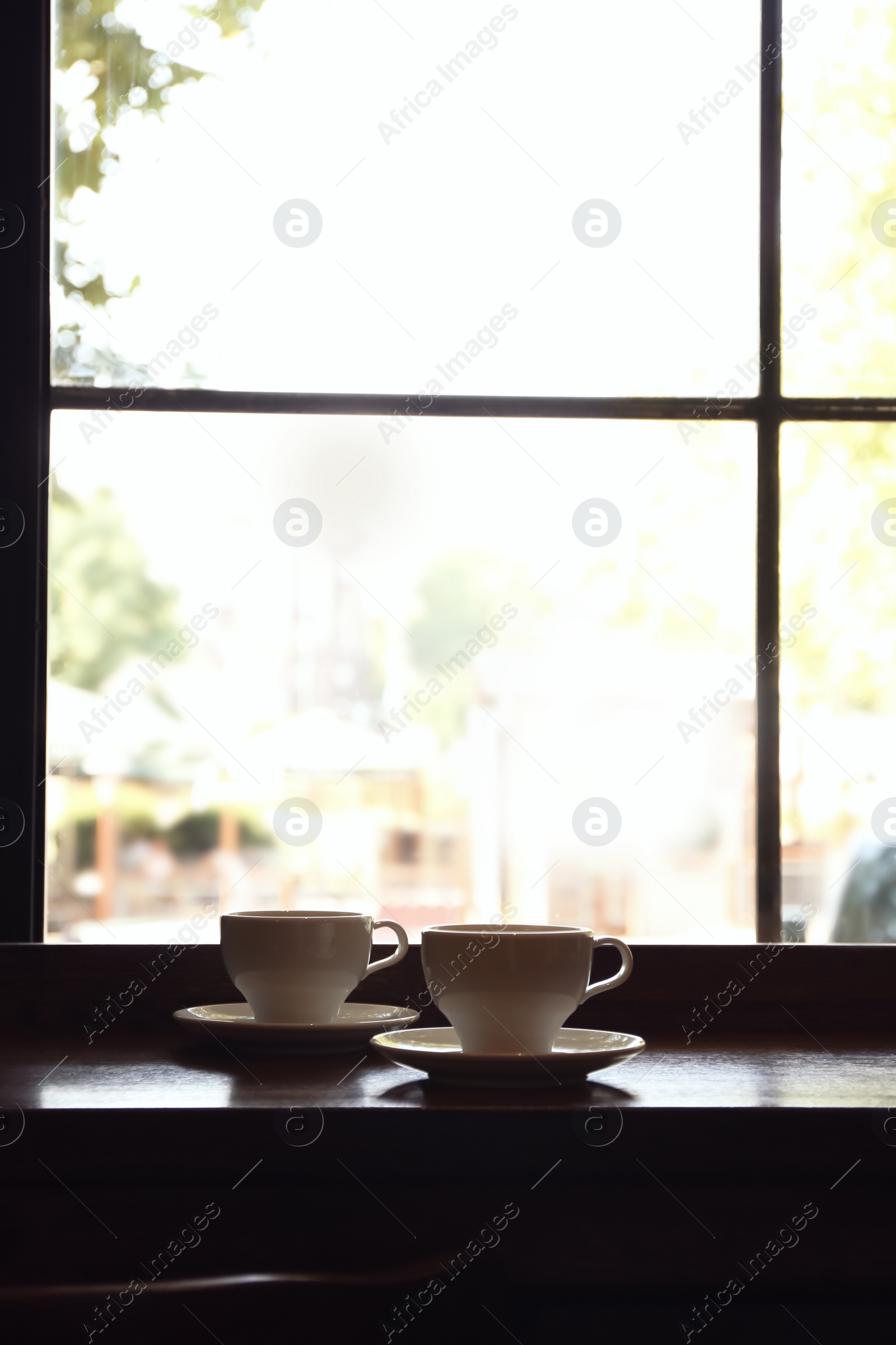 Photo of Cups of fresh aromatic coffee on table near window