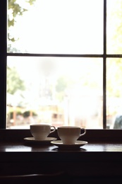 Photo of Cups of fresh aromatic coffee on table near window