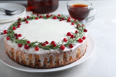Traditional Christmas cake decorated with rosemary and cranberries on light table