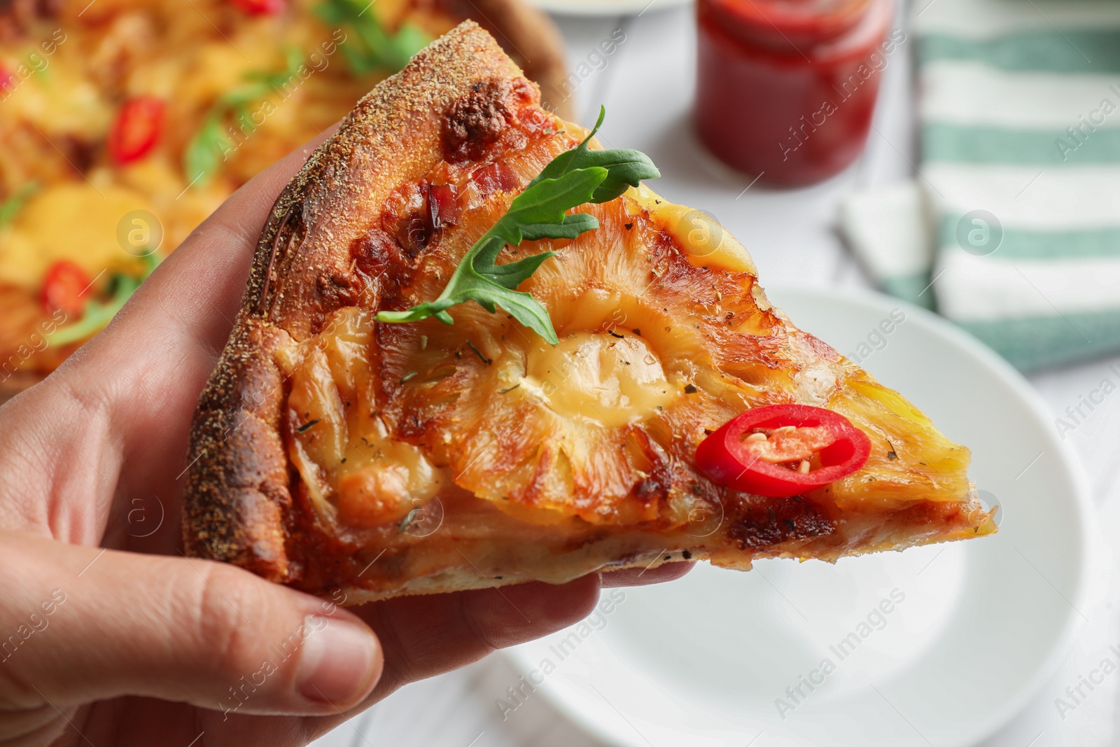 Photo of Woman holding piece of delicious Hawaiian pizza with pineapple, closeup