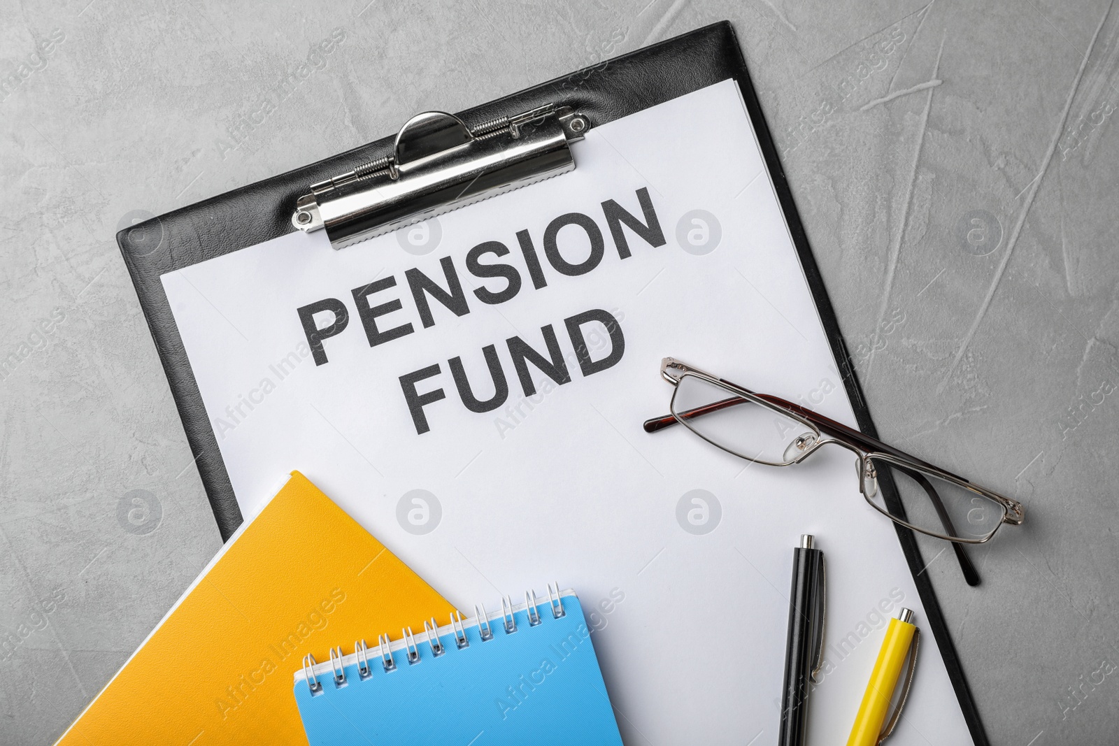 Photo of Stationery, notebooks, glasses and paper with words PENSION FUND on table, flat lay