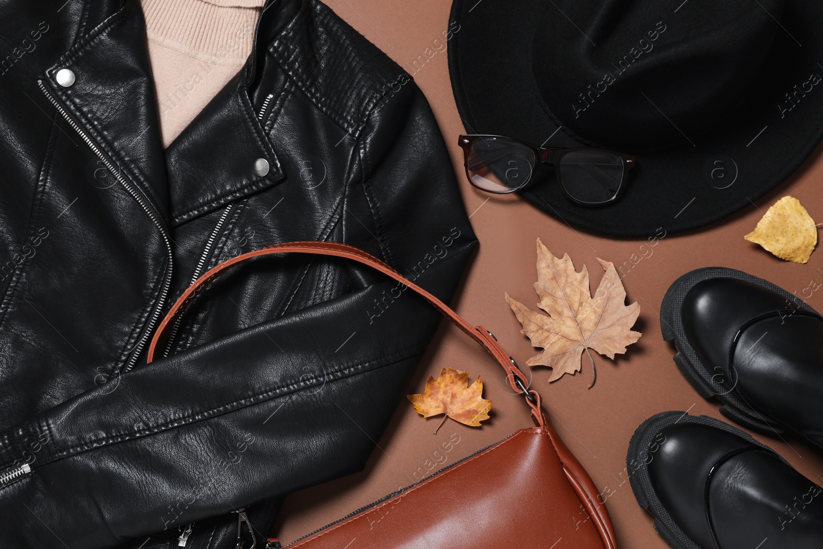Photo of Flat lay composition with stylish hat and autumn clothes on brown background