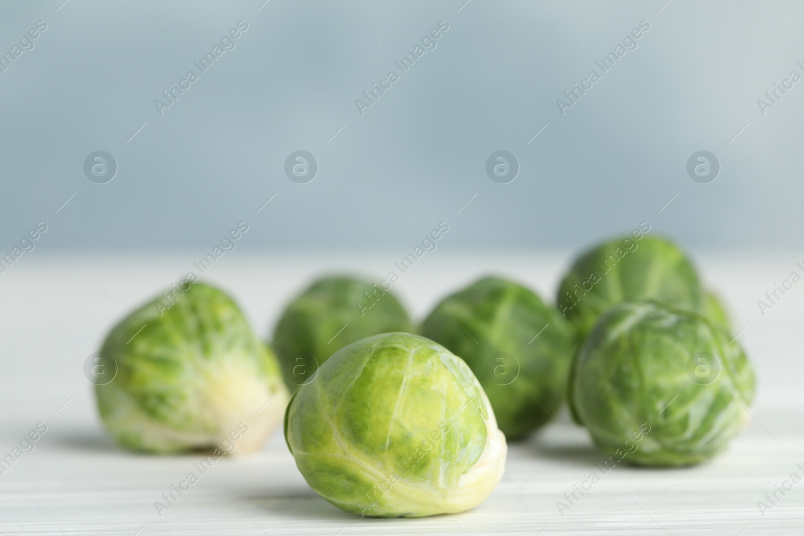 Photo of Fresh Brussels sprouts on white wooden table, closeup