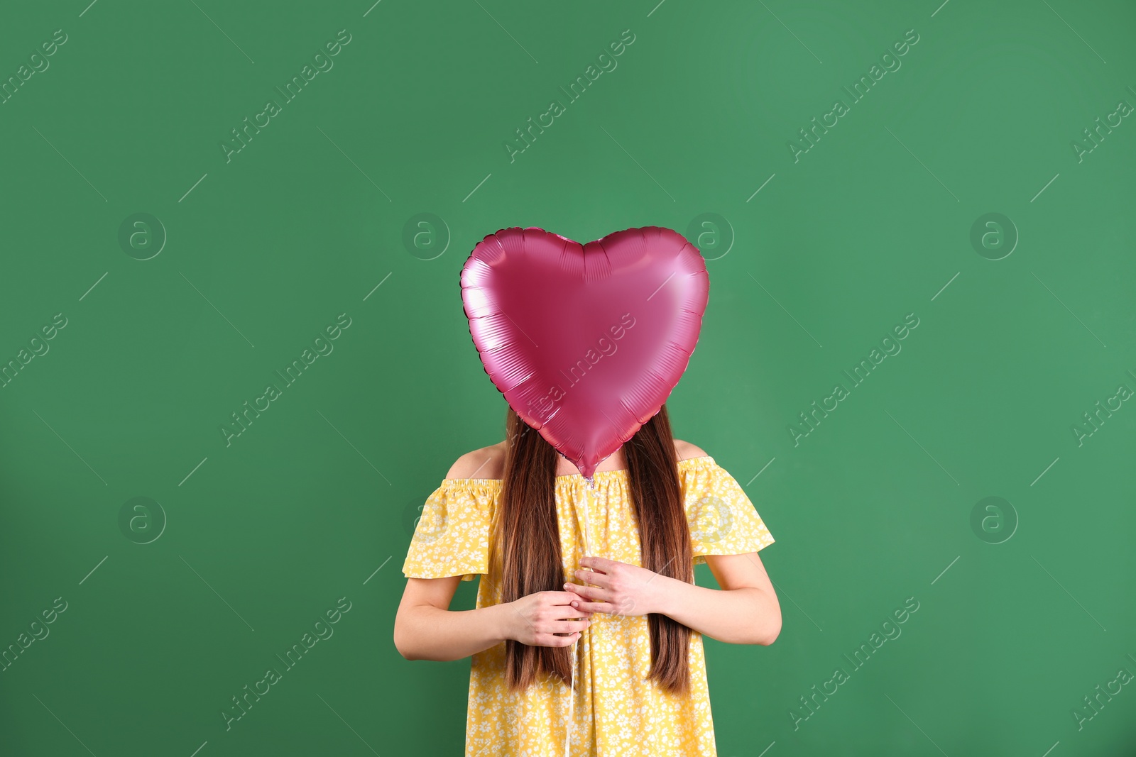 Photo of Young woman with heart shaped balloon on color background