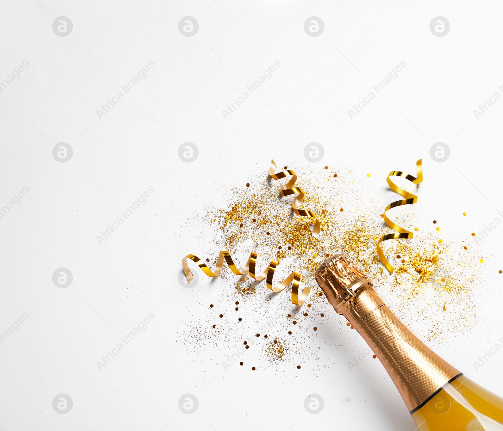 Photo of Bottle of champagne with gold glitter, confetti and space for text on white background, top view. Hilarious celebration