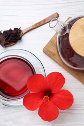 Delicious hibiscus tea and flowers on white wooden table, flat lay