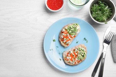 Delicious sandwiches with caviar, cheese, avocado and microgreens on white wooden table, flat lay. Space for text