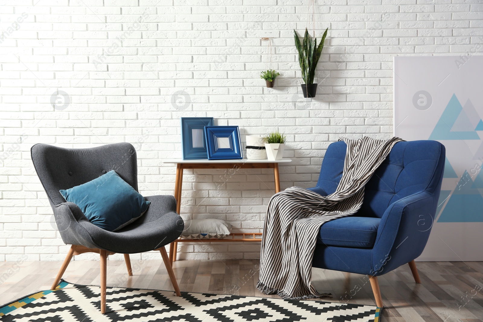 Photo of Modern interior with cozy armchairs and table near brick wall