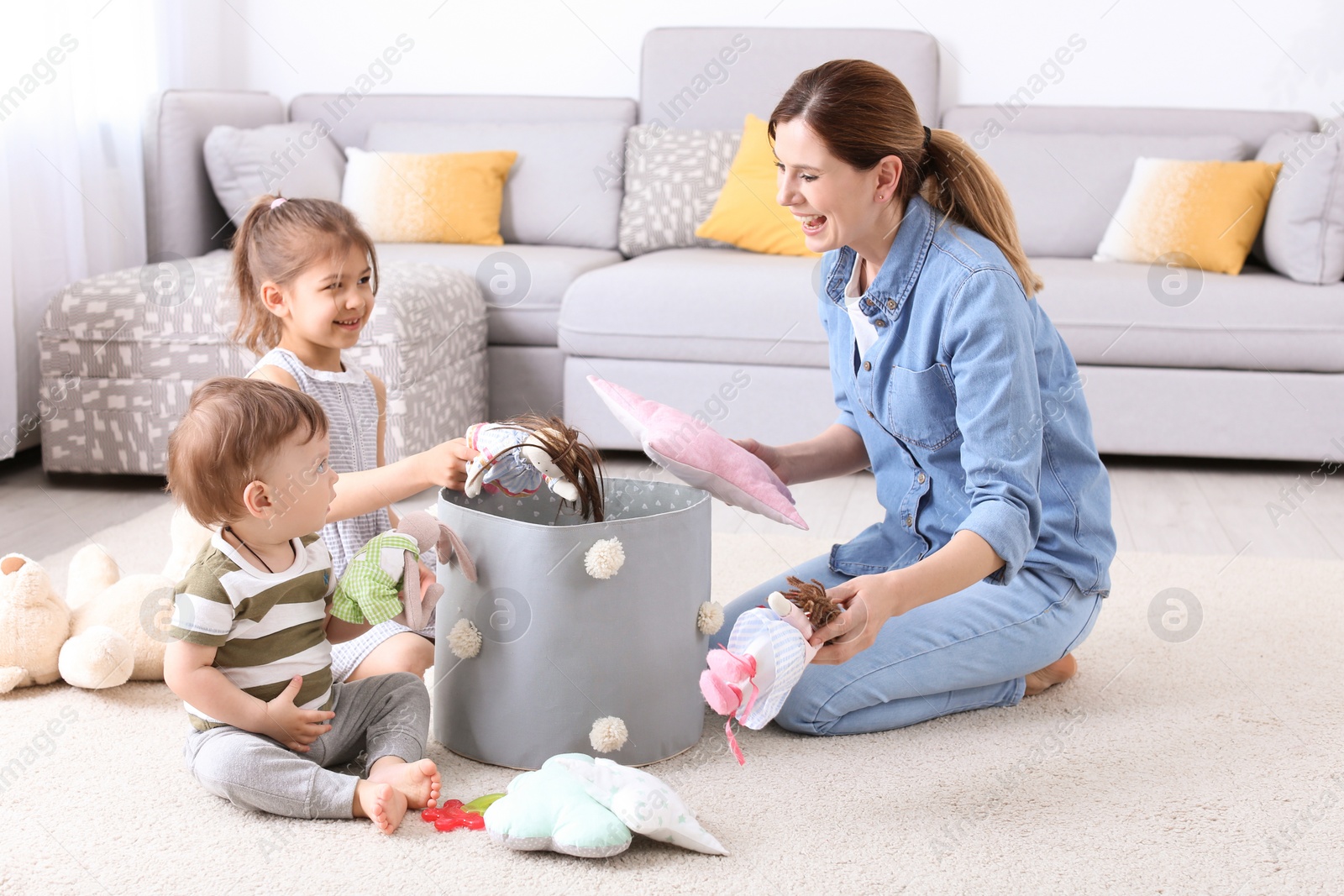 Photo of Housewife and children picking up toys after playing at home