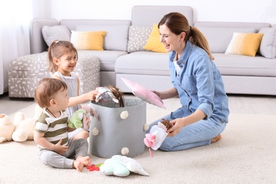 Photo of Housewife and children picking up toys after playing at home