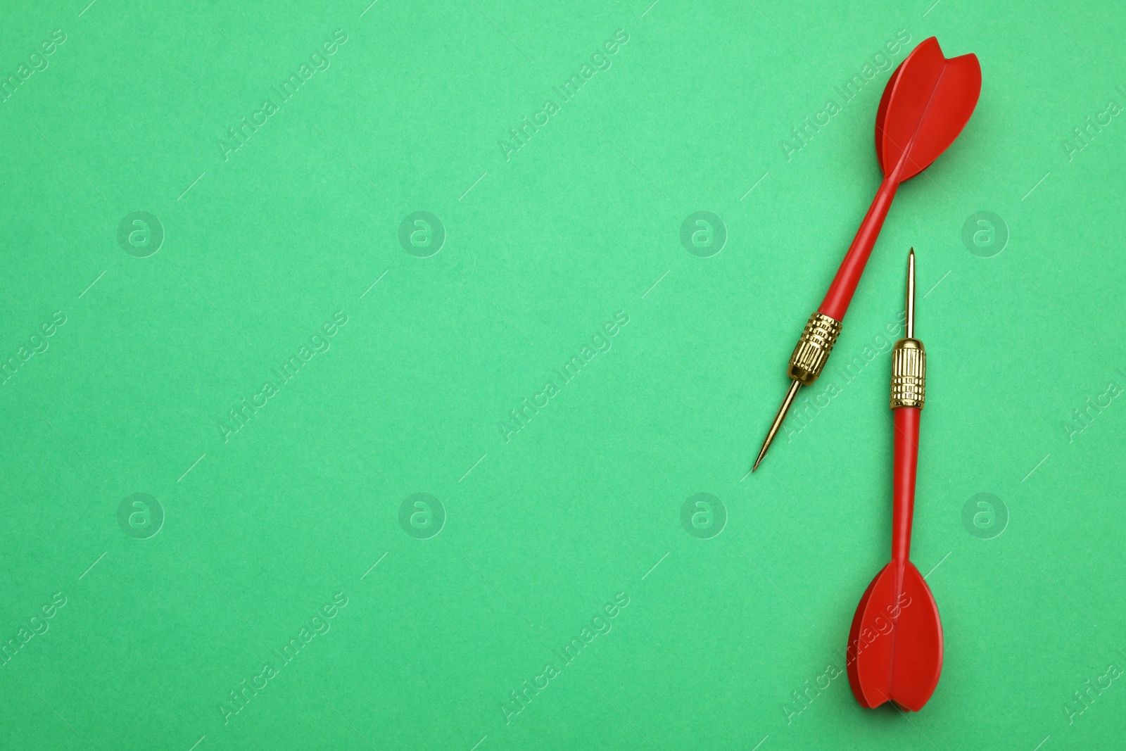 Photo of Red dart arrows on green background, flat lay with space for text