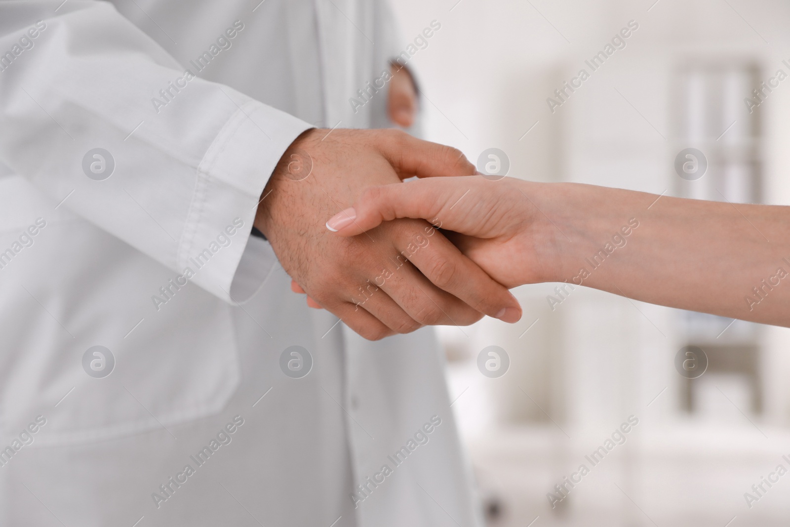 Photo of Doctors greeting woman with handshake in clinic, closeup