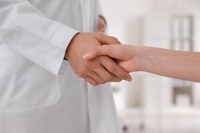 Doctors greeting woman with handshake in clinic, closeup