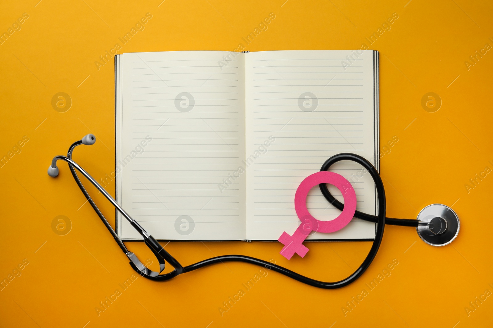 Photo of Female gender sign, open notebook and stethoscope on orange background, flat lay. Women's health concept