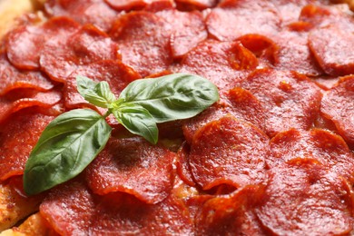 Photo of Tasty pepperoni pizza with basil as background, closeup