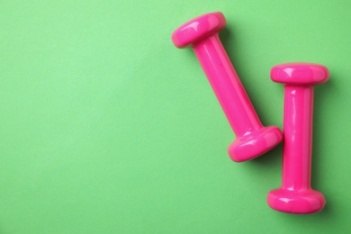 Photo of Bright dumbbells and space for text on color background, flat lay. Home fitness
