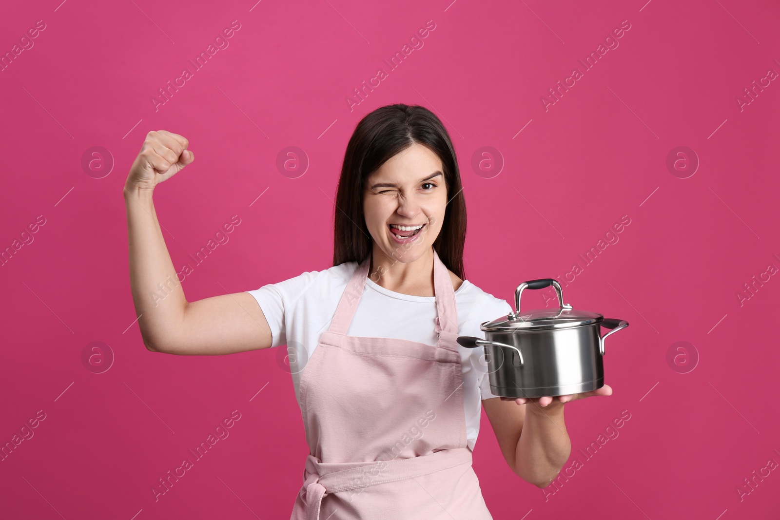 Photo of Happy young woman with cooking pot on pink background