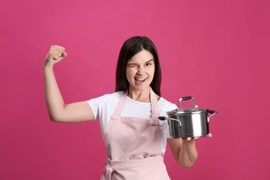 Happy young woman with cooking pot on pink background