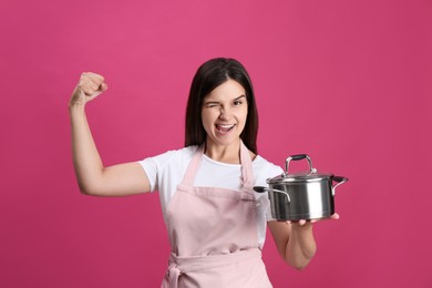 Photo of Happy young woman with cooking pot on pink background