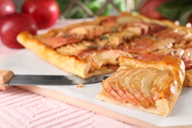 Freshly baked apple pie with knife on table, closeup