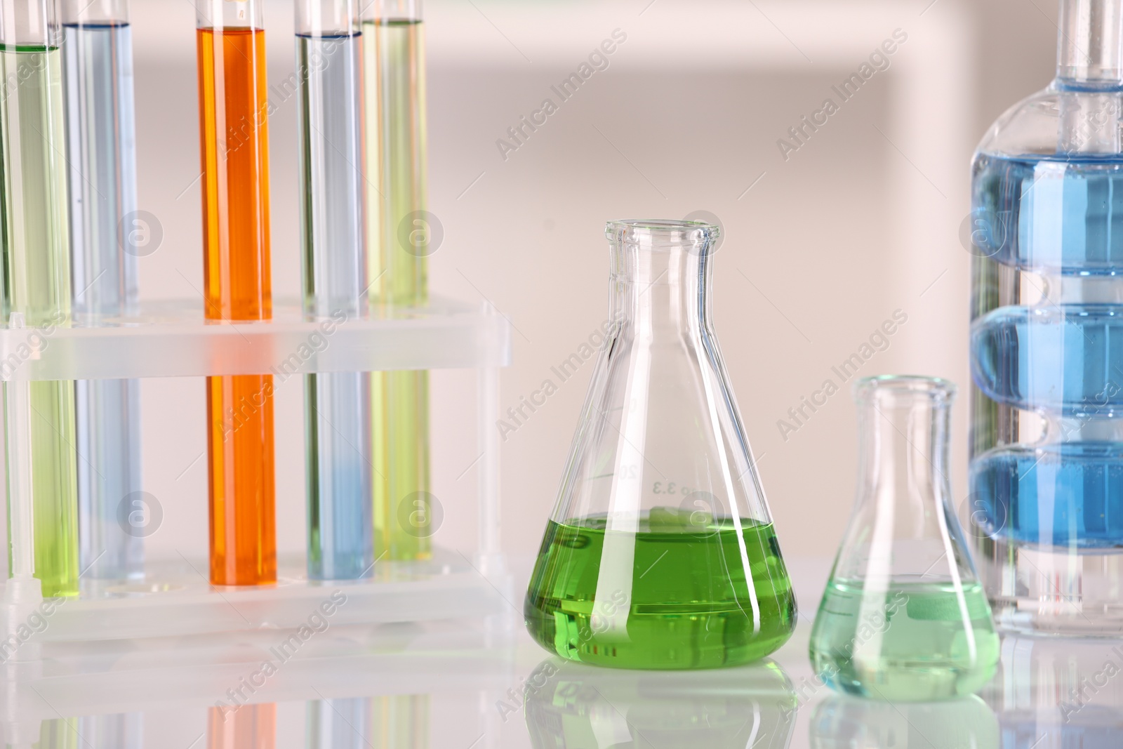 Photo of Laboratory analysis. Different glassware with liquids on white table against blurred background