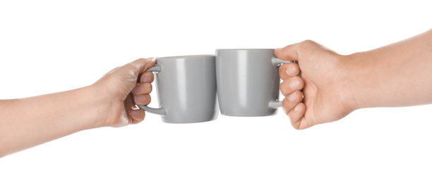 Photo of Women clinking light grey cups on white background, closeup