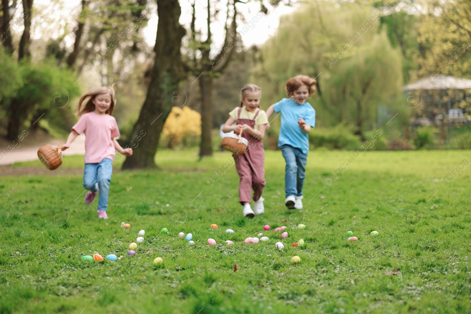 Photo of Easter celebration. Little children hunting eggs outdoors, selective focus