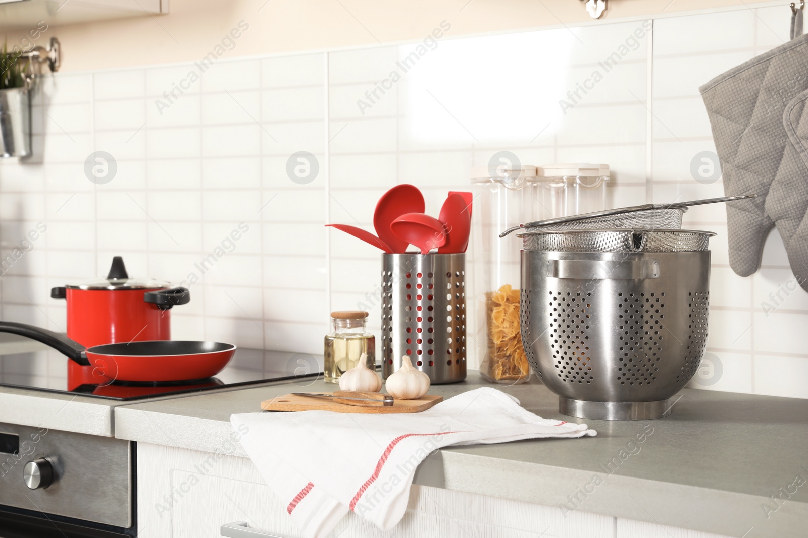 Photo of Set of clean cookware, utensils and products on table in modern kitchen