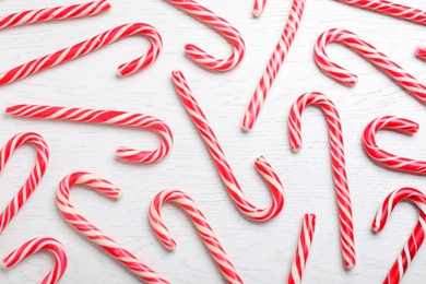 Sweet Christmas candy canes on white wooden 
background, flat lay