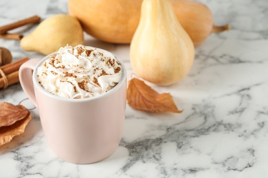 Cup with tasty pumpkin spice latte on white marble table. Space for text